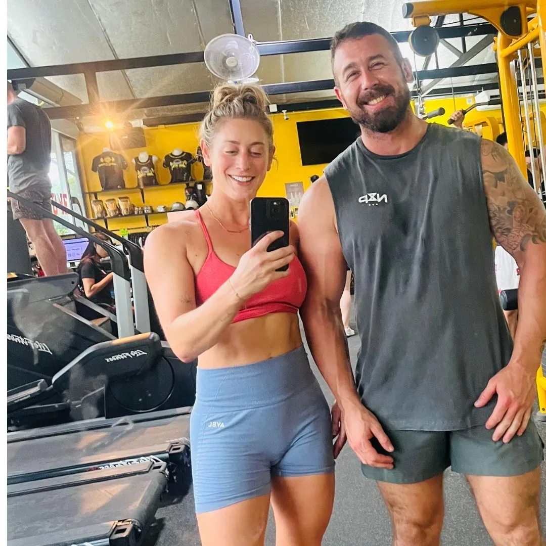 female and male in gym clothes taking a photo in the gym together